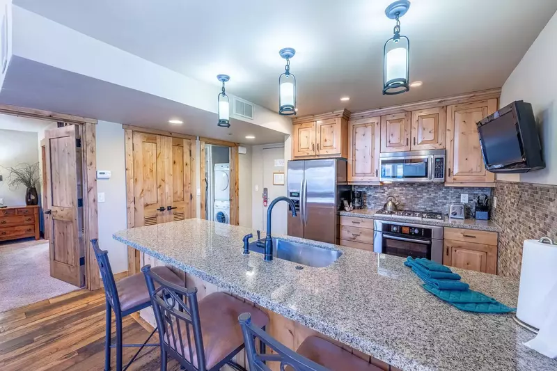 The home's spacious kitchen features upgraded appliances, granite countertops, and a breakfast bar with seating for 3 guests.