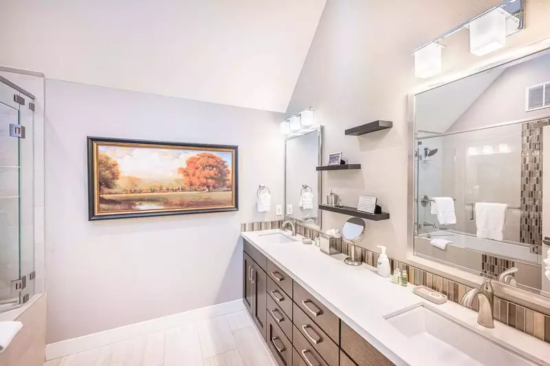 Elegant En Suite Primary Suite Bathroom Features Dual Vanities, Oversized Tub w Glass Shower and Vaulted Ceilings