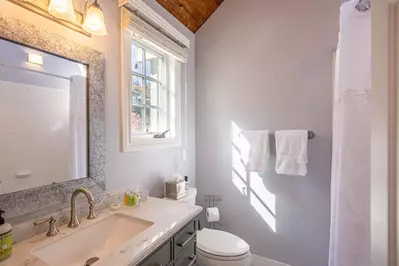The primary en suite bathroom has a beautiful new hardwood vanity that is topped with a white granite counter top.