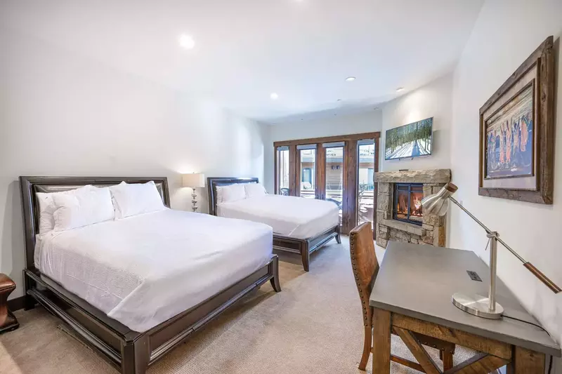 The spacious guest suite features two comfortable queen sized beds, a dedicated workspace, and a gas fireplace