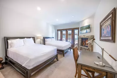 The spacious guest suite features two comfortable queen sized beds, a dedicated workspace, and a gas fireplace