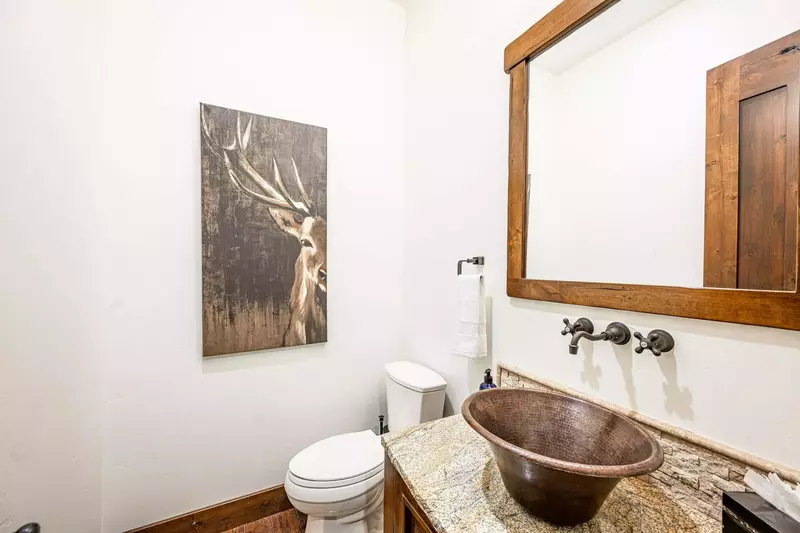 The half bathroom is just off the kitchen and features a unique sink centered on a high end granite countertop