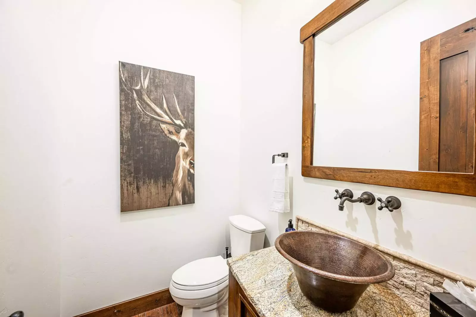 The half bathroom is just off the kitchen and features a unique sink centered on a high end granite countertop