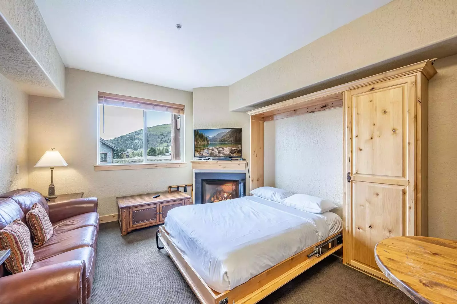 The warm and inviting living area features a comfortable leather sofa, gas fireplace, HDTV and a Queen sized Murphy bed.