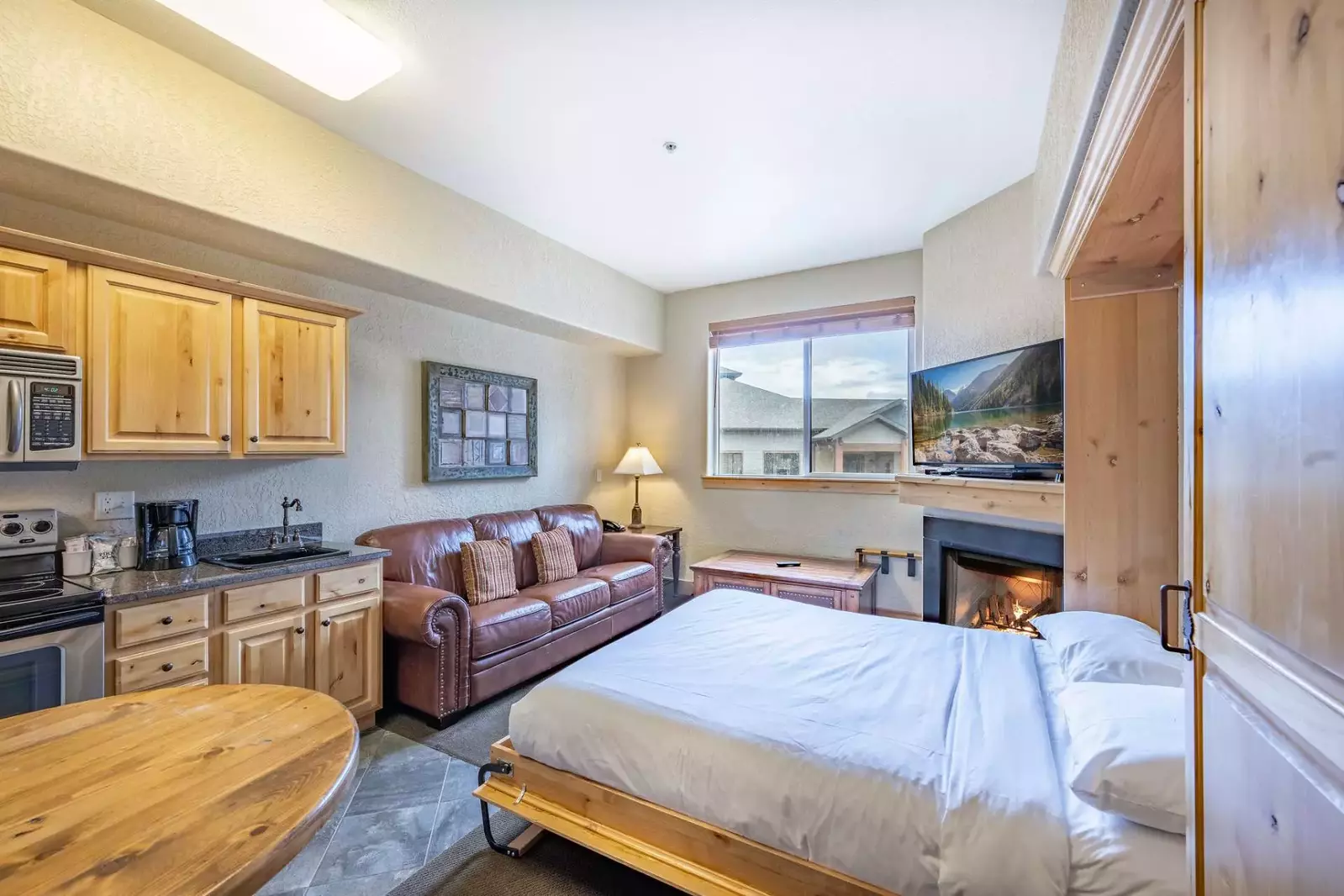 The warm and inviting living area features a comfortable leather sofa, gas fireplace, HDTV and a Queen sized Murphy bed.