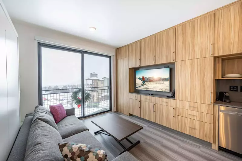 A comfortable sofa, a coffee table that converts into a dining table with seating for four, and plenty of modern cabinetry provides an efficient space