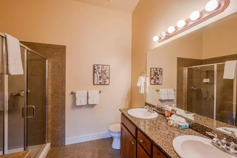 Second bathroom with walk-in glass shower and twin vanities