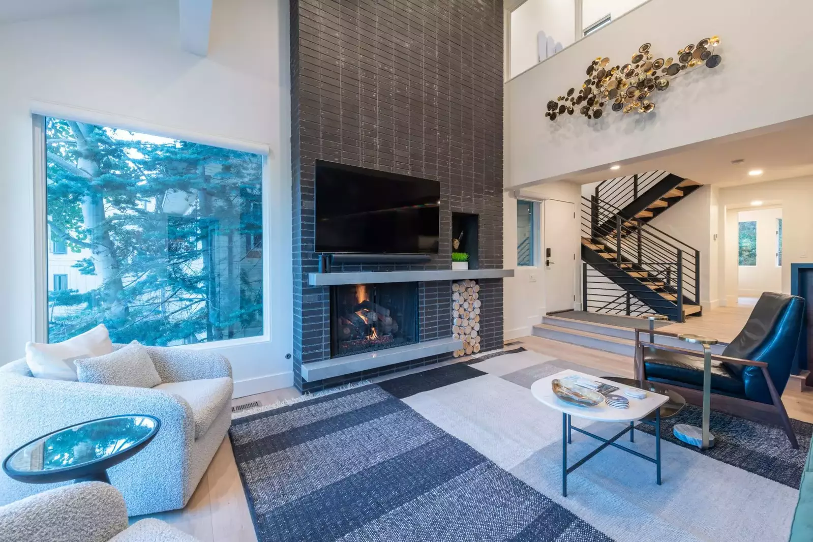 Large gas fireplace with stunning brick wall, 65" wall-mounted HD Smart TV and lots of light through new and enlarged windows