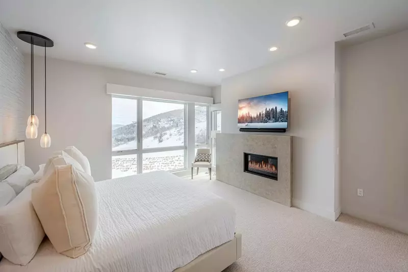 The elegant primary retreat boasts oversized windows showcasing the sweeping mountain views and a romantic fireplace