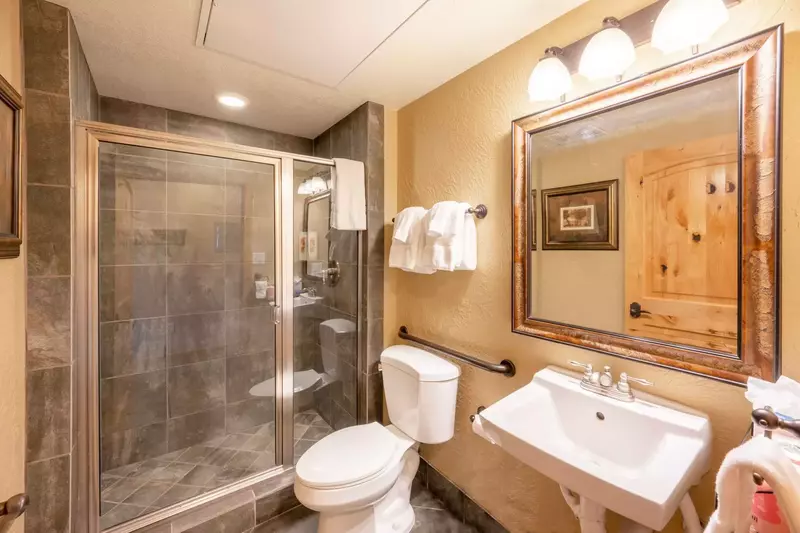This is the en suite bathroom for the guest suite (with the 2 queen beds). It features a walk in glass shower, gray tile work, plush, professionally l