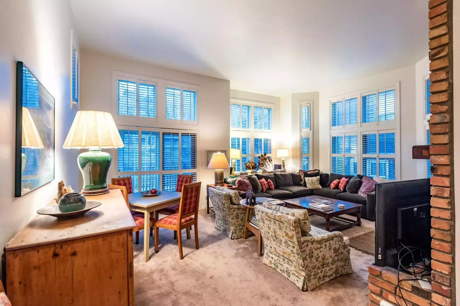 The family room features a comfortable and push L-shaped couch that surrounds a floor to ceiling brick fireplace and HDTV.