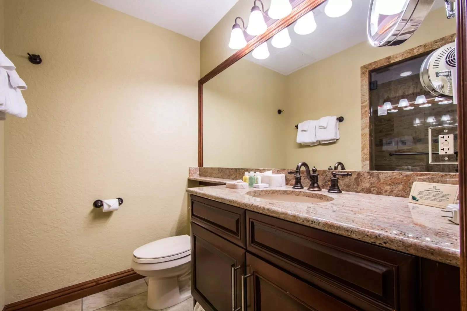 The warm mountain design continues into the bathroom with white & brown granite counters, bronze fixtures & finishes, rainfall shower & large mirror.