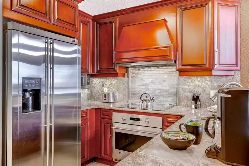 Gourmet kitchen with granite counters and a surface stove accented with stone backsplace.