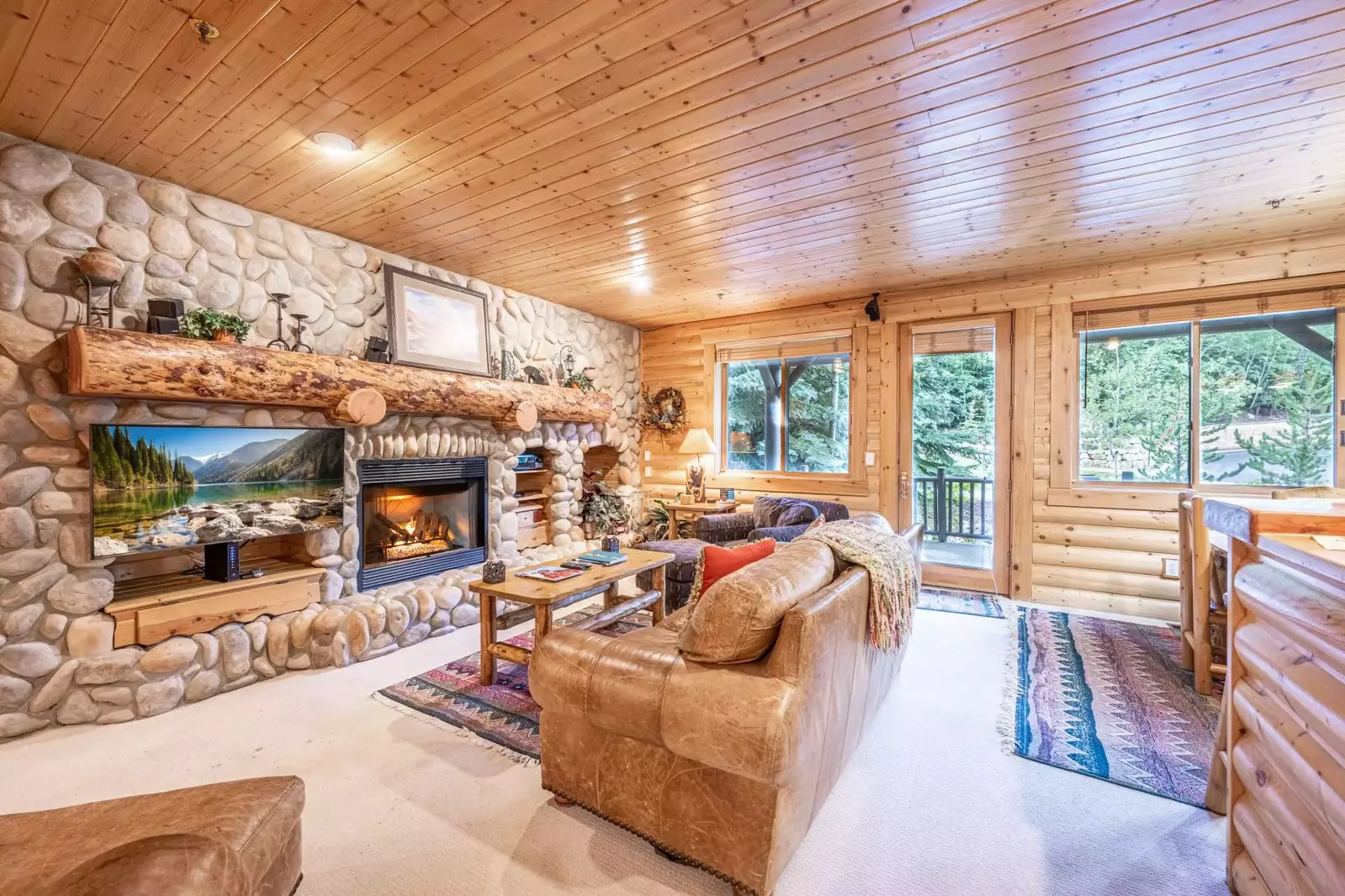 Spacious and inviting living area with Leather sofa (sleeper), comfortable chairs, river stone encased gas fireplace, HDTV with cable television and W