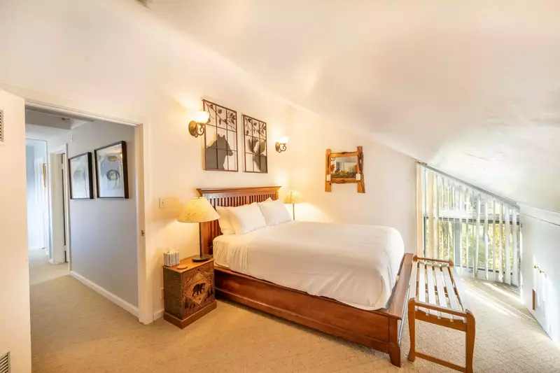 The primary suite is located at the end of the hall & has a queen size bed with hardwood bed frame & two hand carved nightstands with lamps.