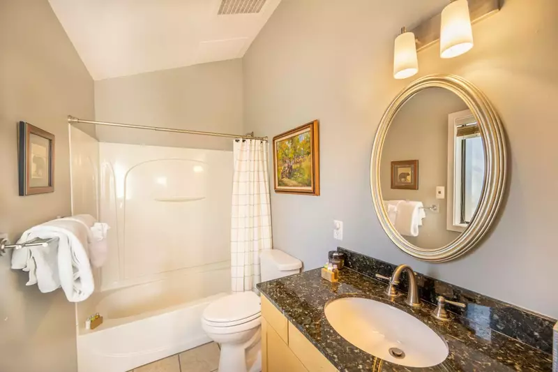 The second bathroom features black & emerald granite countertops, stainless steel finishes & lighting, toilet, vaulted ceilings, & shower & bathtub.