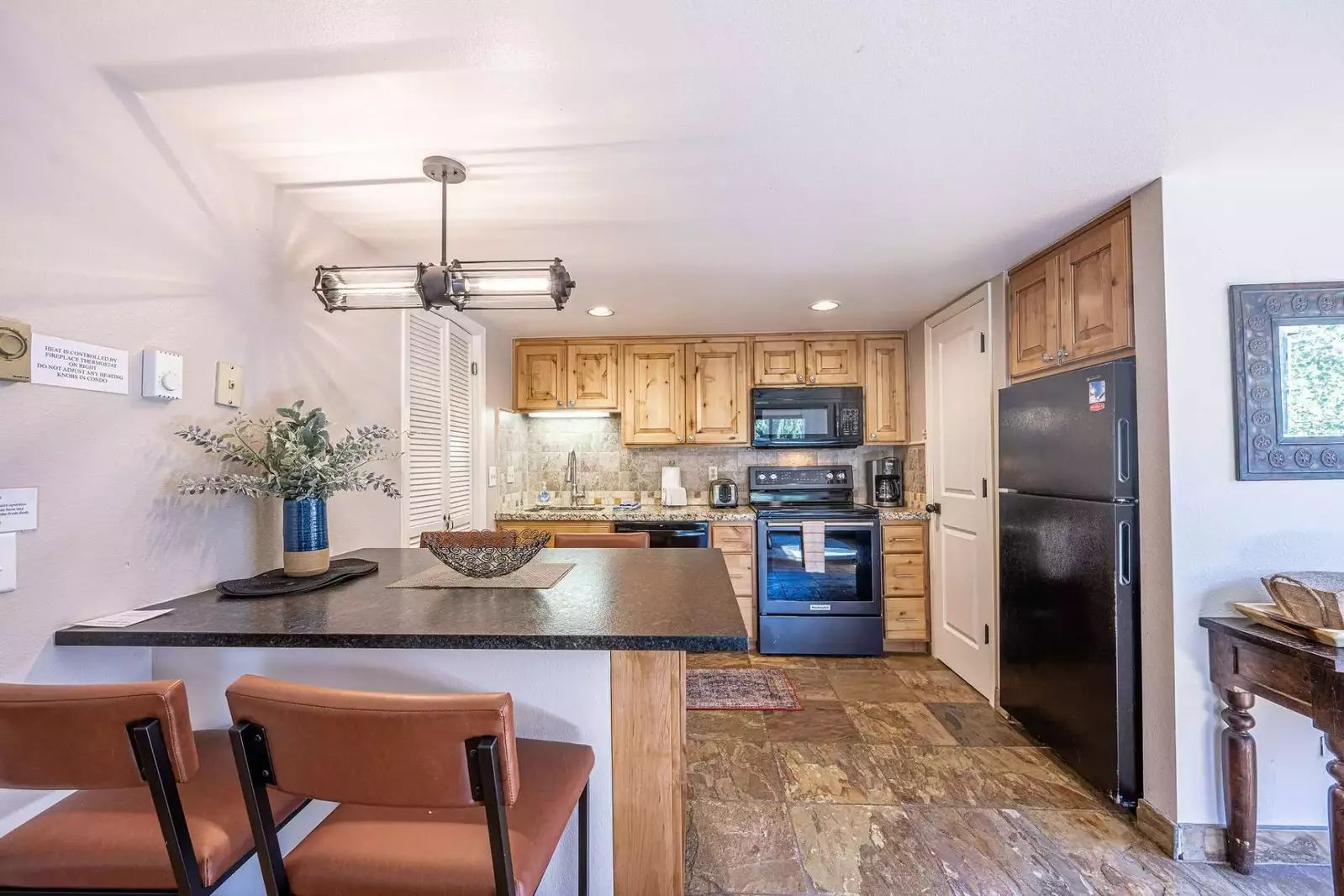 The renovated kitchen has an open layout and features new hardwood cabinets, granite countertops and fixtures as well as stone tile flooring.