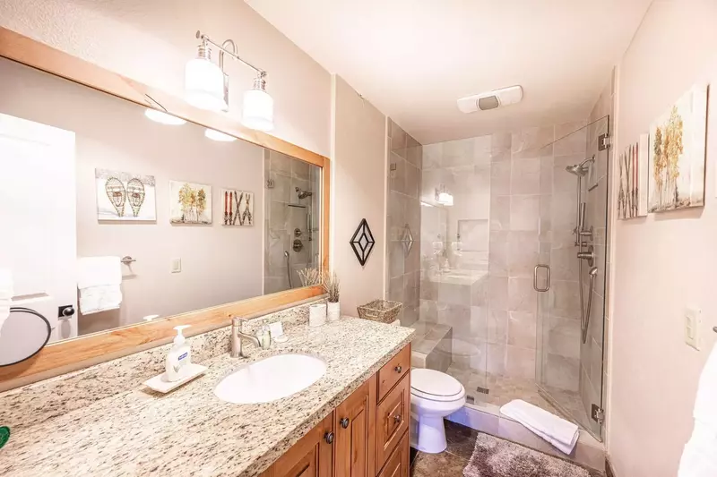 The first floor primary suite bathroom has been beautifully updated with granite countertops, luxurious walk in glass shower with dual shower head