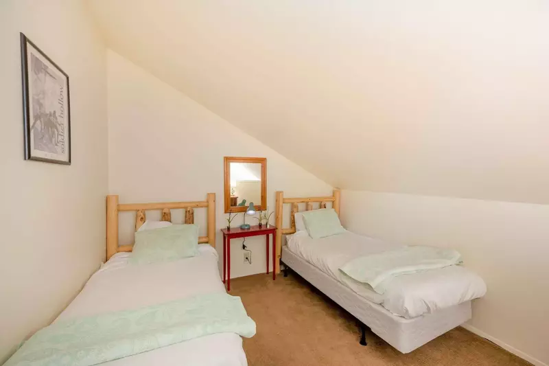The loft bedroom features two twin beds, large dresser and nightstand. Both bedrooms on the upper floor share the bathroom