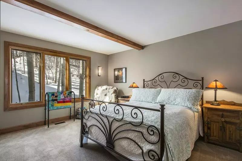 Second guest room with breathtaking views of nature, artistic wrought iron bedframe and queen bed with inviting pillows and linens.