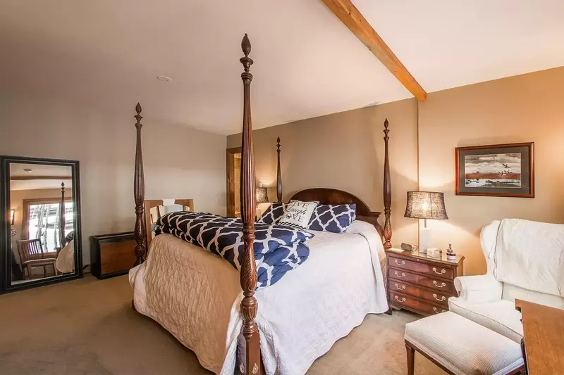 A large mirror reflects upon the lush bedding and furnishing in the master bedroom.