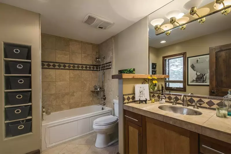 Master bathroom with large mirror, two-toned wooden draws, storage baskets and shower and tub.