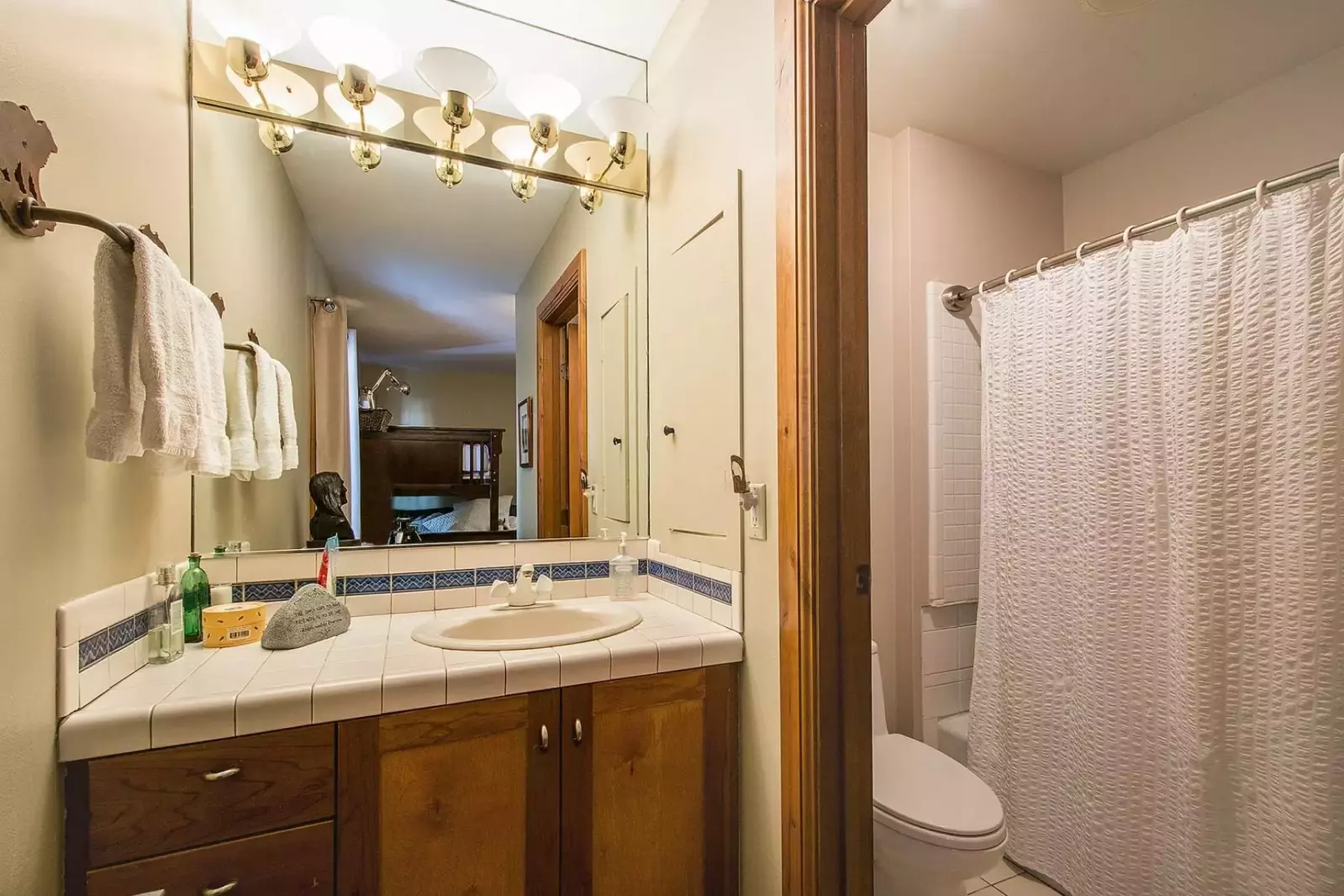 Guest bathroom with two toned cabinets, tile counter and seperate shower area.