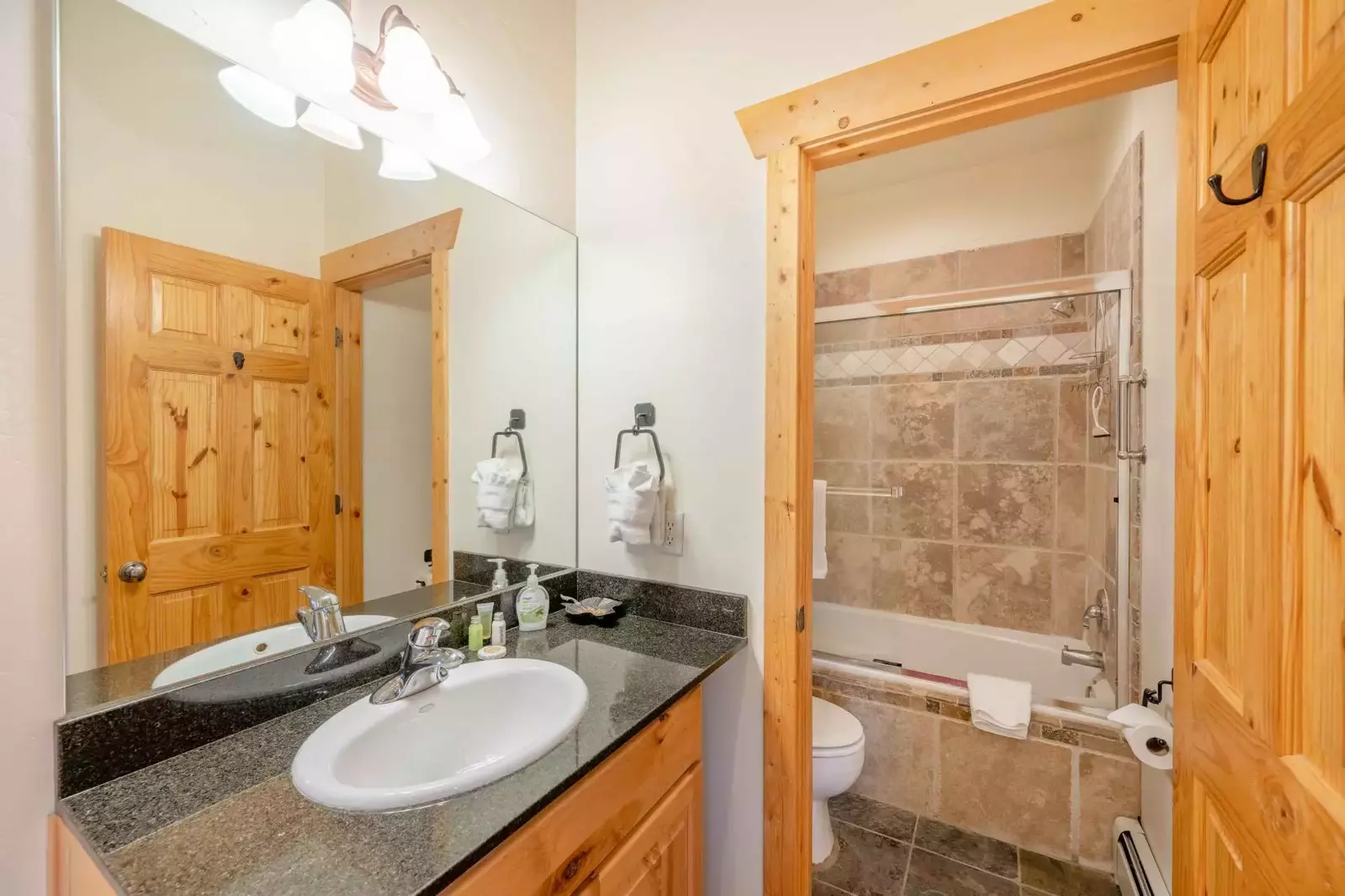 The primary suite bathroom features dark granite counters, stainless steel fixtures, Kohler sink and a fully enclosed soaker tub and shower.