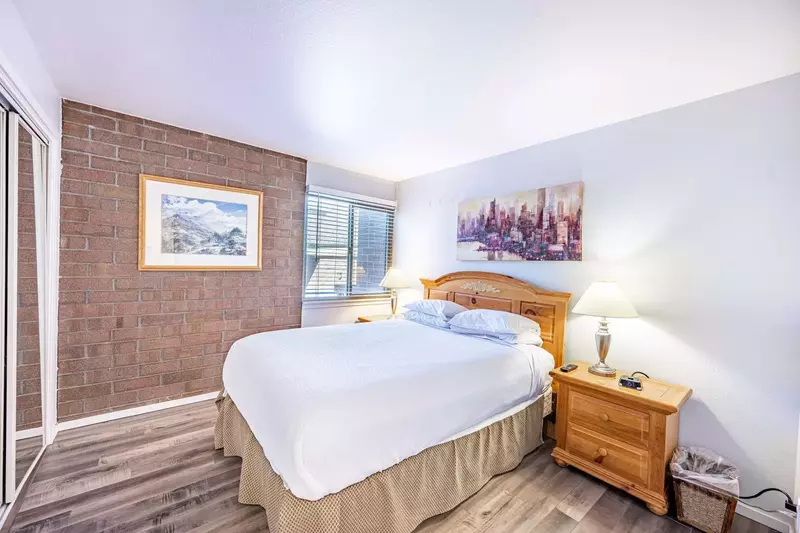 The first guest suite has an exposed brick wall and hardwood flooring - it has a warm and inviting feel. It features a Queen bed and two hardwood nigh