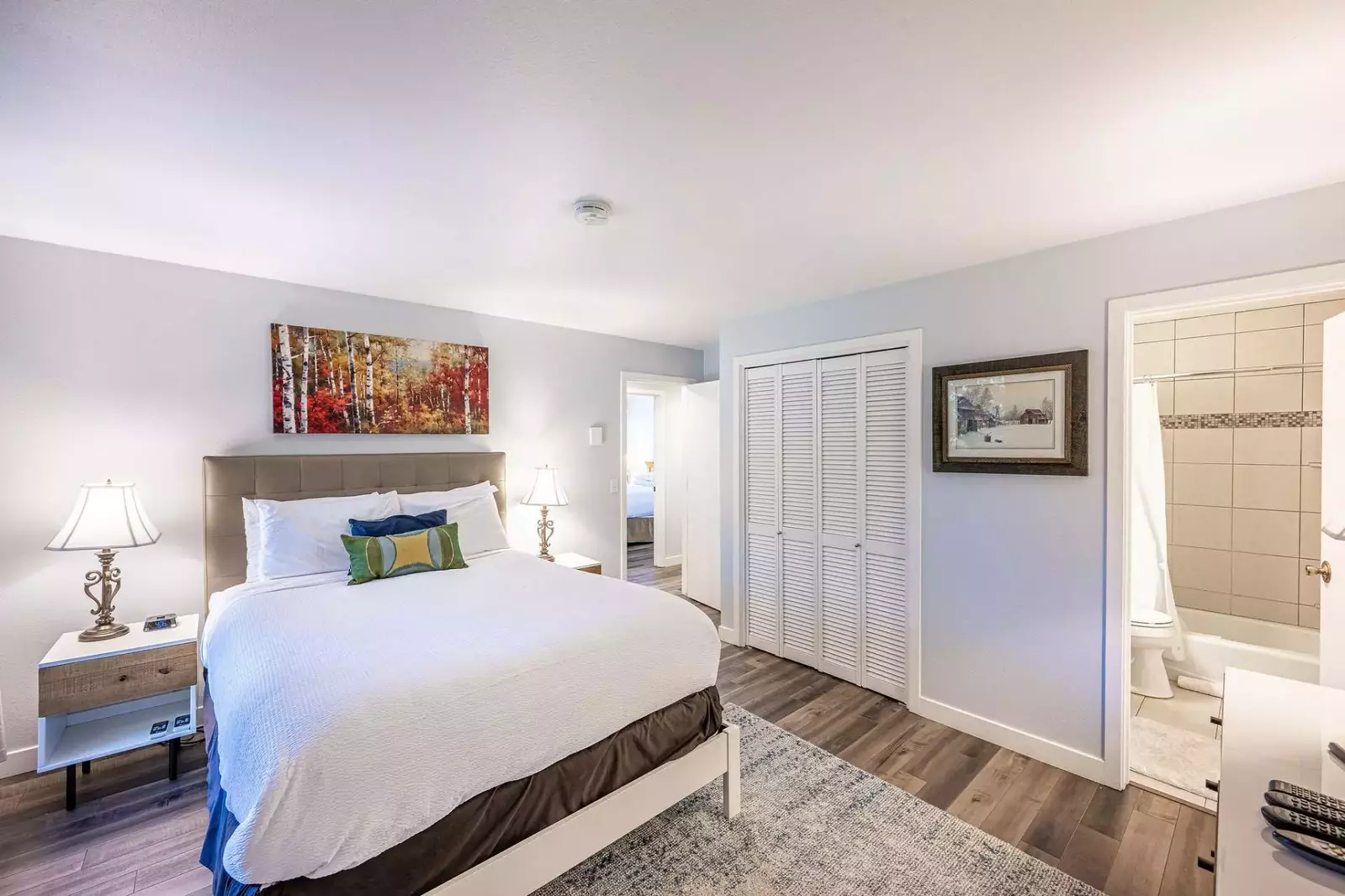 The primary suite features hardwood flooring, a new designer area rug, two modern nightstands, each with their own reading lamp. The closet houses the