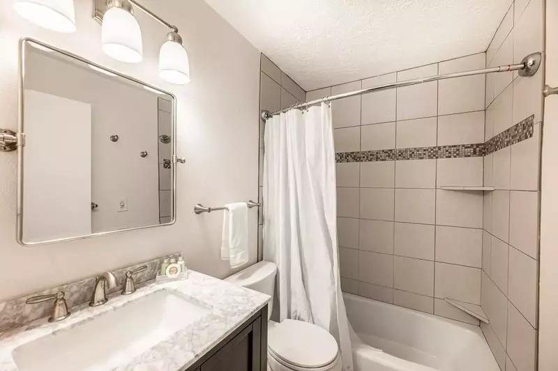 The primary suite en suite bathroom was recently updated with new designer tile in the shower/bath, new hardwood vanity with marble top and custom mir