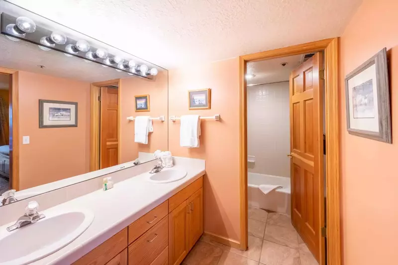 The spacious guest bathroom has a large double vanity, perfect for families with a separate area for the tub, toilet, and shower