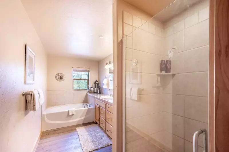 The Primary Suite Features a Spa Like En Suite Bathroom w Large Jetted Tub, Walk in Glass Shower, Hardwood Flooring, Double Vanity w Spacious Countert