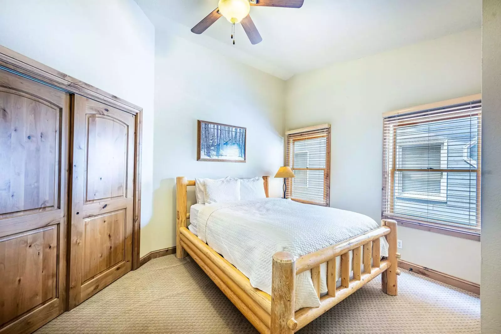 Upper level guest suite features a queen size bed with custom log pole bed frame, dressers and en suite bathroom.