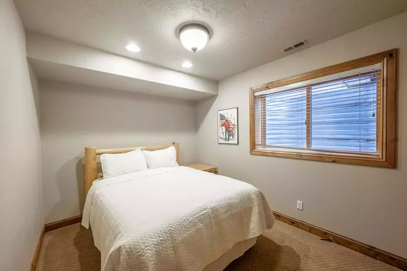 Lower Level guest suite features a queen size bed with custom log pole bed frame, dressers and shared updated bathroom with the twin bedroom