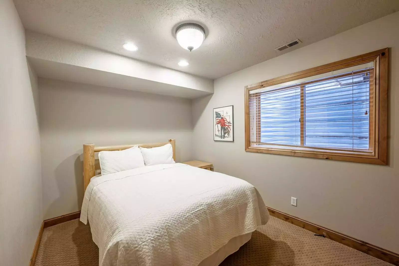 Lower Level guest suite features a queen size bed with custom log pole bed frame, dressers and shared updated bathroom with the twin bedroom