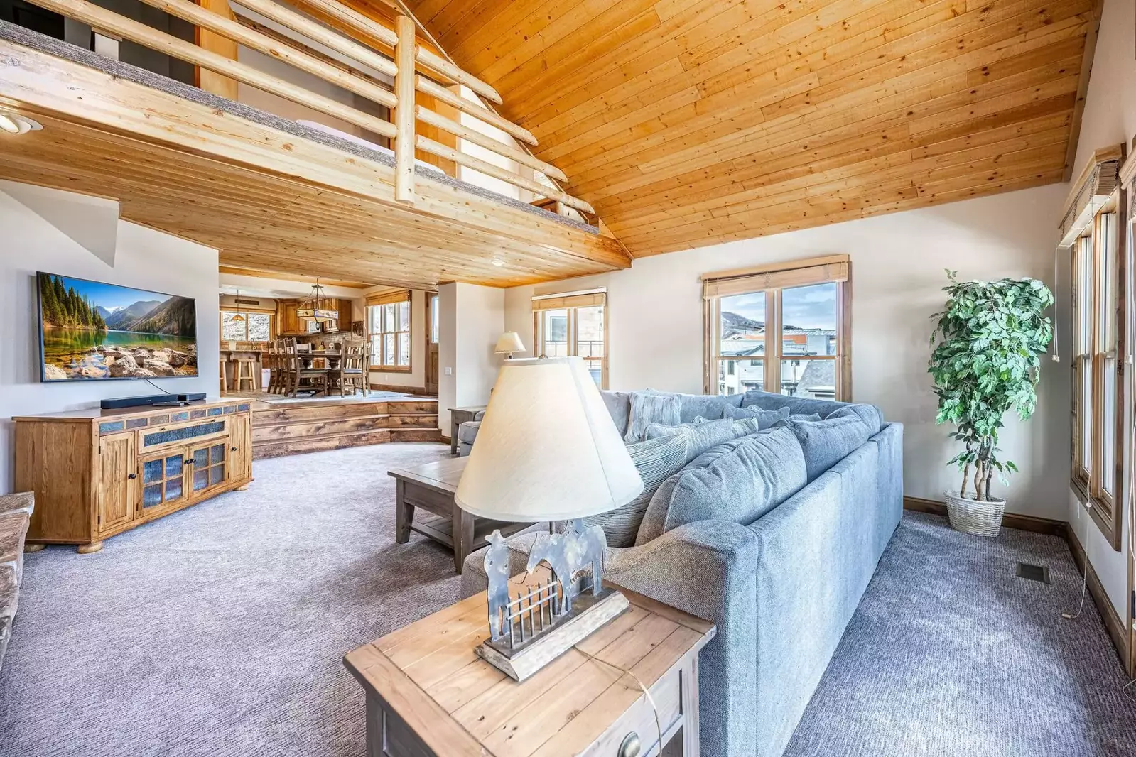 The living room is equipped a comfortable sofas embracing the gas fireplace with floor to ceiling stonework and the entertainment center