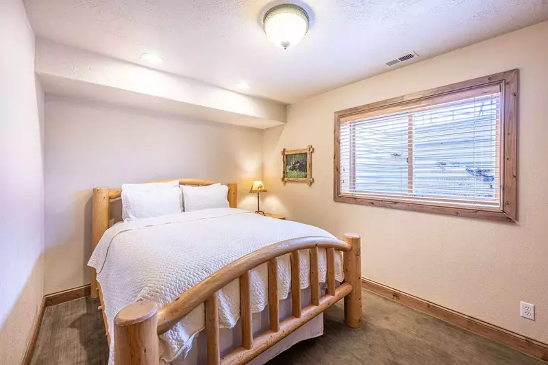 Guest suite features a queen size bed with custom log pole bed frame, dressers and a shared bathroom
