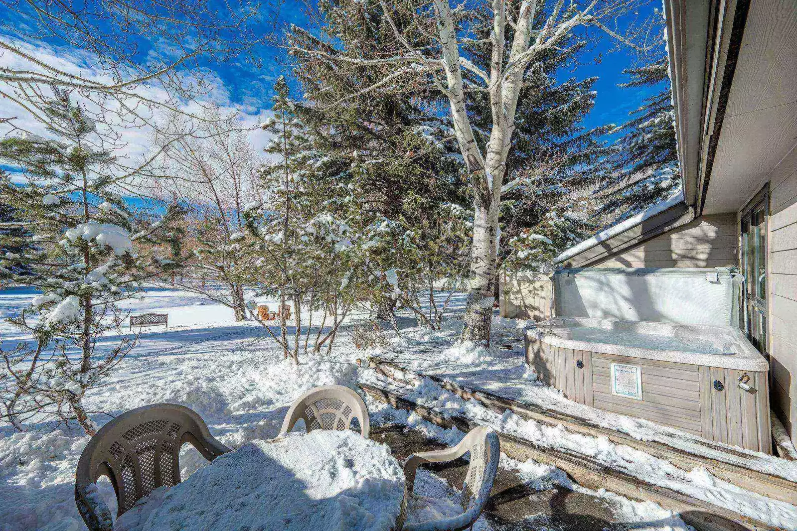 Private deck with chairs and private hot tub overlooking the frozen lake.