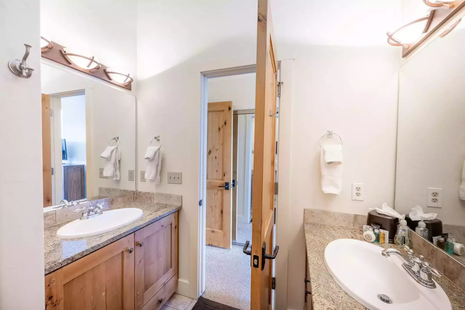 The primary suite en suite bathroom features two separate granite vanities and a walk in glass shower.