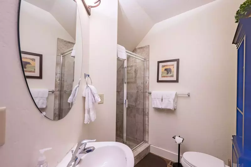 Located Just off the Kitchen is a Full Bathroom w Pedestal Sink, Toilet and Walk- In Glass Shower