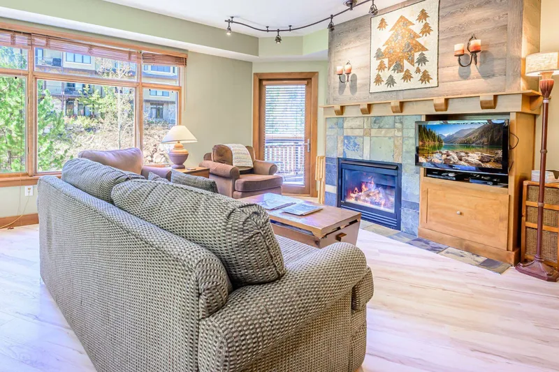 Cozy up next to the fireplace in our open-concept, Park City living room with new hardwood flooring and updated furniture.