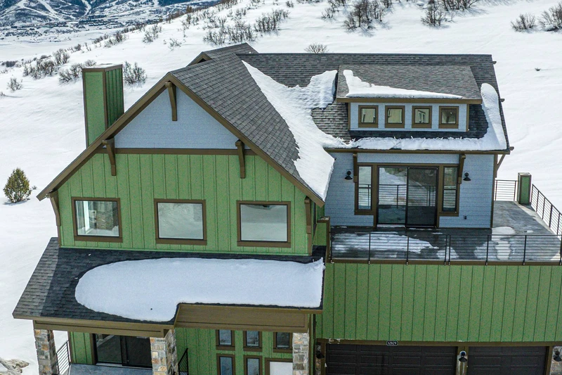 This beautiful aerial shot of the home shows the private balcony off the primary bedroom with views of the mountains