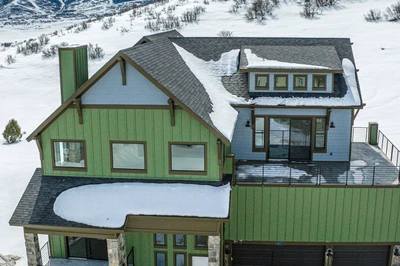 This beautiful aerial shot of the home shows the private balcony off the primary bedroom with views of the mountains