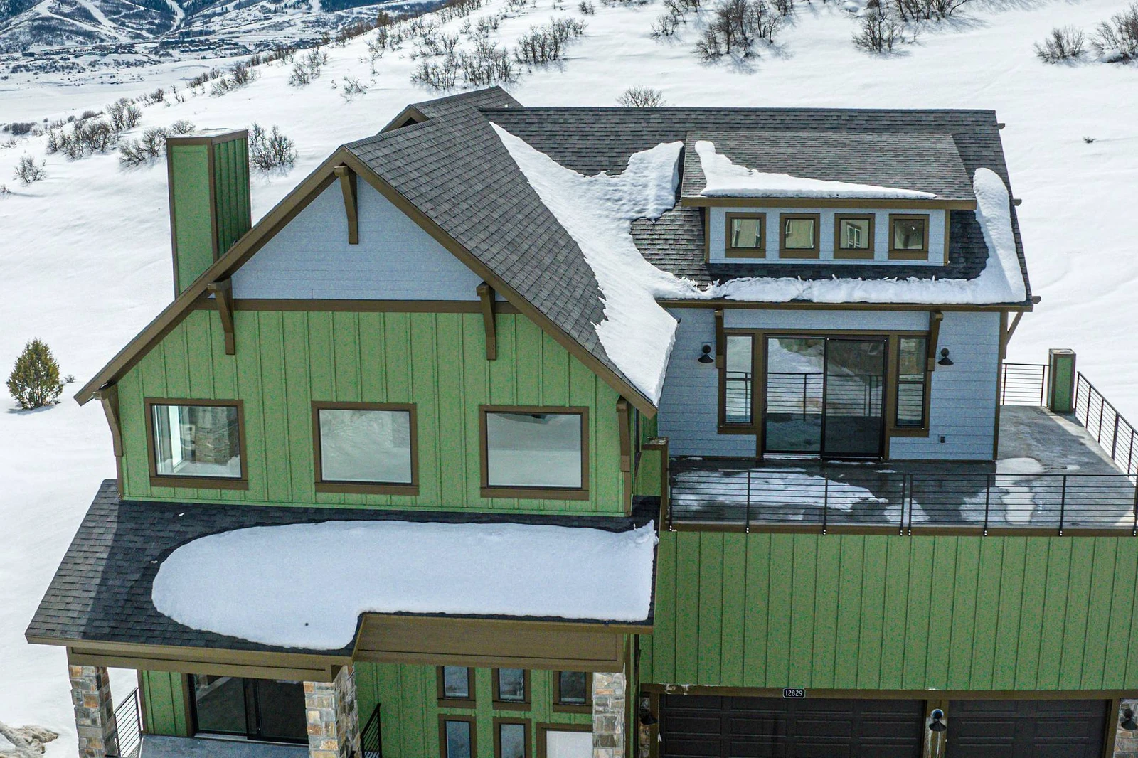 This beautiful aerial shot of the home shows the private balcony off the primary bedroom with views of the mountains