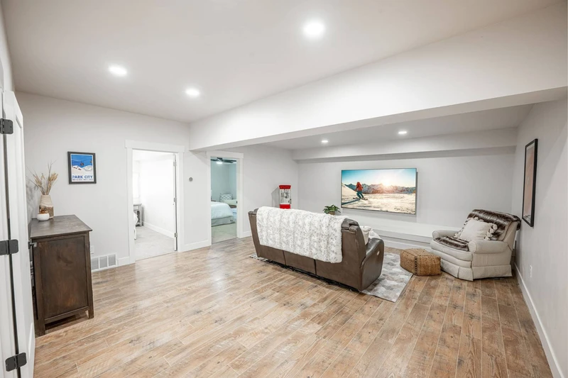 The spacious theater room of the home features a large flat screen tv with a popcorn maker and is featured on the middle level of the home