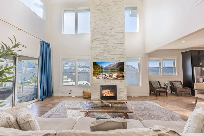 Great Room — two-story stacked stone fireplace, vaulted ceiling, clerestory windows | The Gathering House at Jordanelle