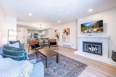 Living room with comfortable seating and TV, open to the kitchen and dining area. (alternate angle, looking back towards kitchen from living room)