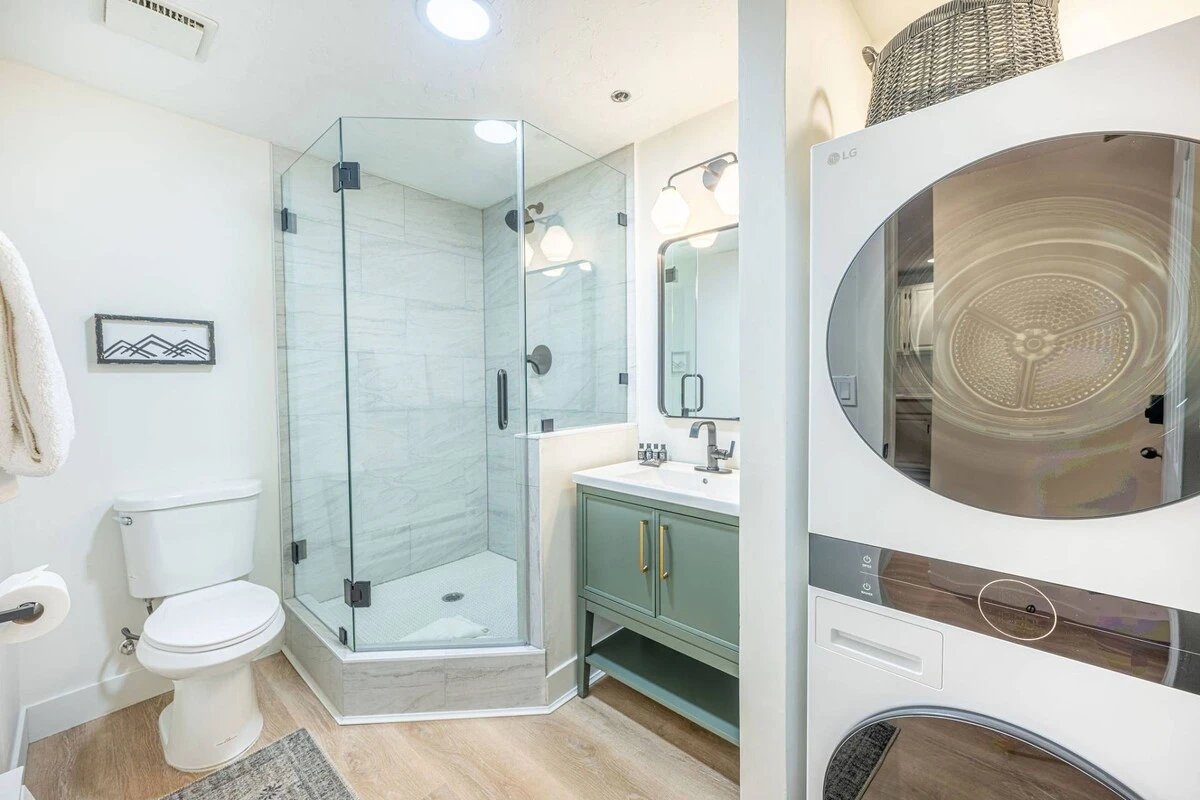 In-home washer and dryer for guest use. Full bathroom with new sage green vanity, walk-in glass shower and toilet