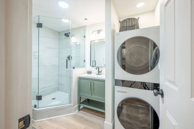 In-home washer and dryer for guest use. Full bathroom with new sage green vanity, walk-in glass shower and toilet